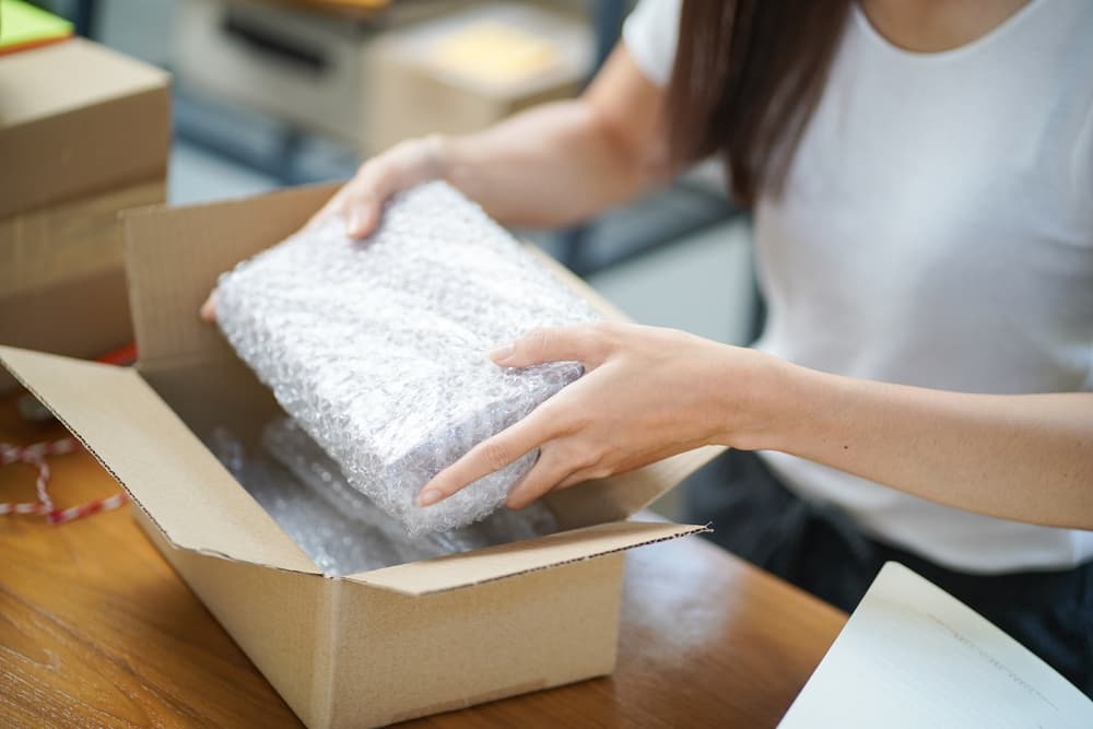 エアクッションで包んだ商品を箱に入れる手元